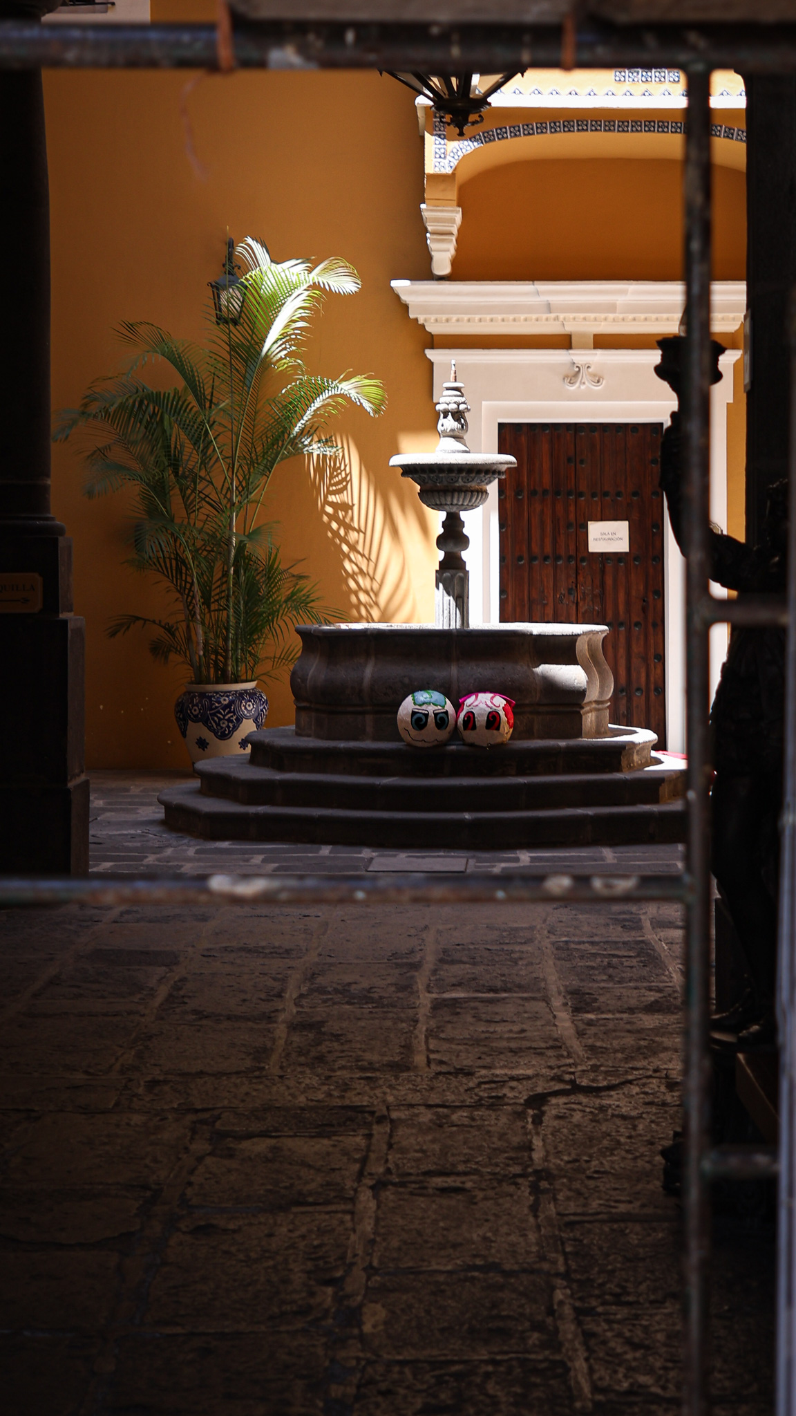 Quiet courtyard fountain topped with two stone spheres, warm interior light