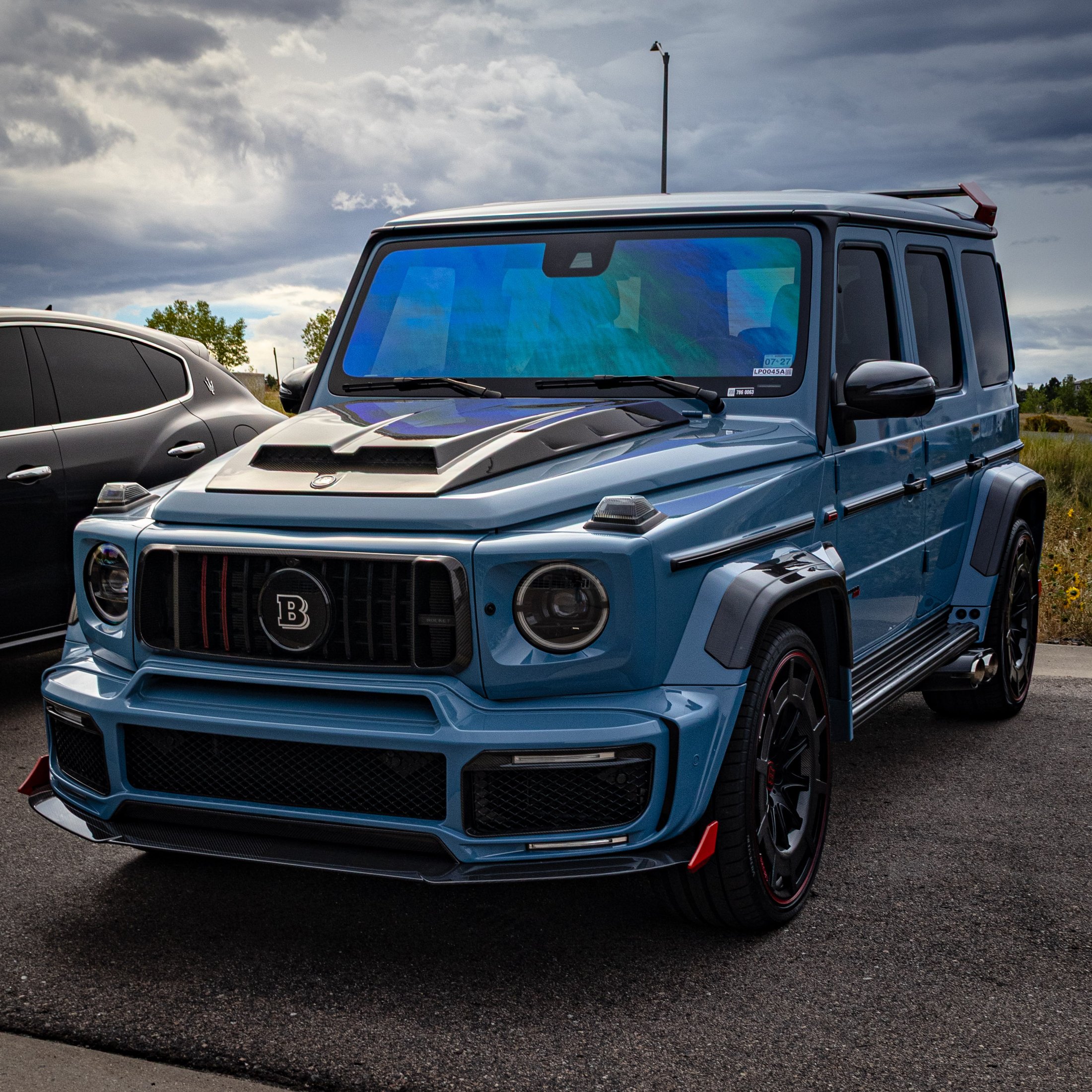 Powder blue BRABUS-widebody Mercedes G-Wagon parked outdoors under a dramatic stormy sky