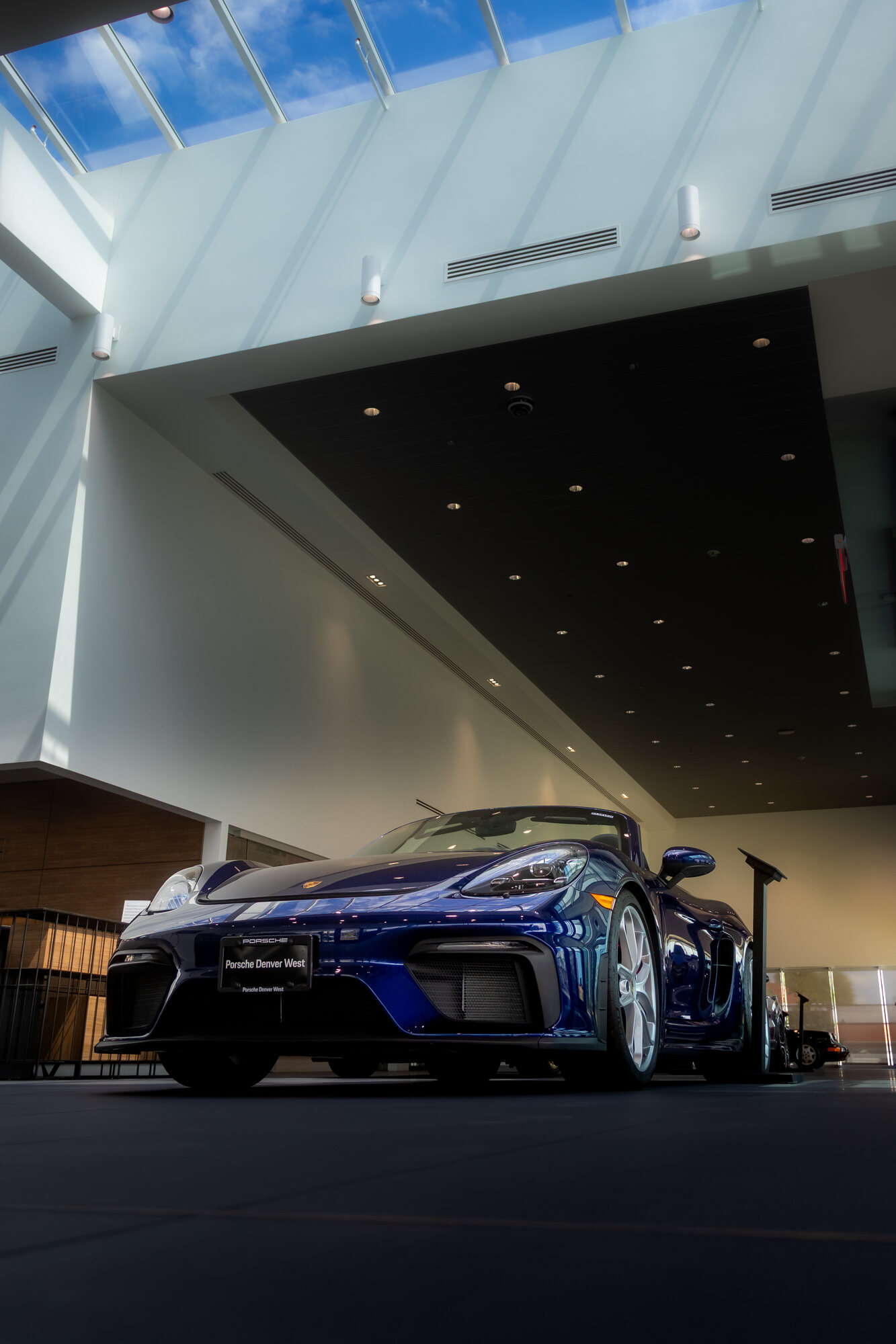 Blue Porsche 718 parked inside a bright, modern showroom